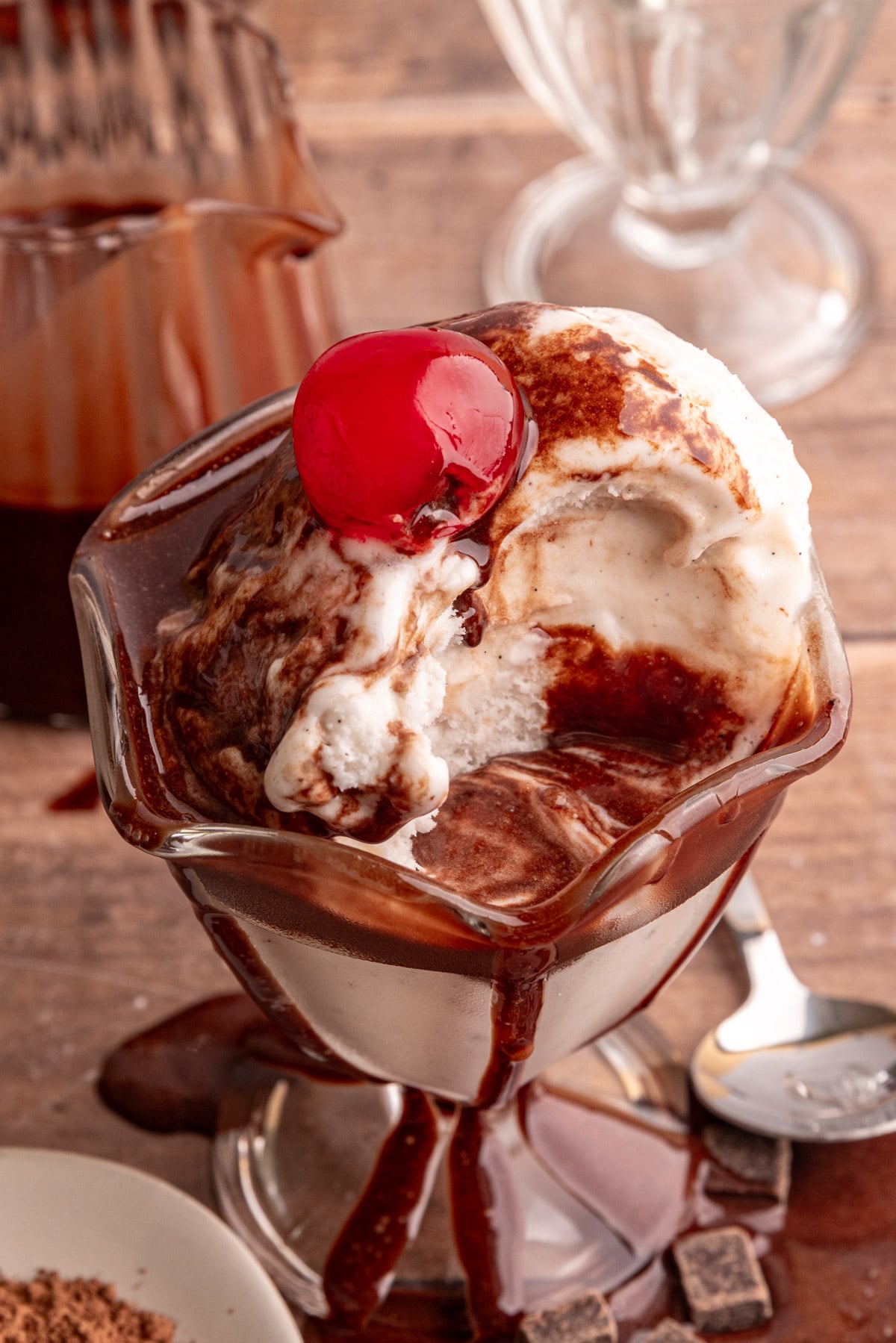 Maple chocolate syrup on a bowl of ice cream with a cherry on top.