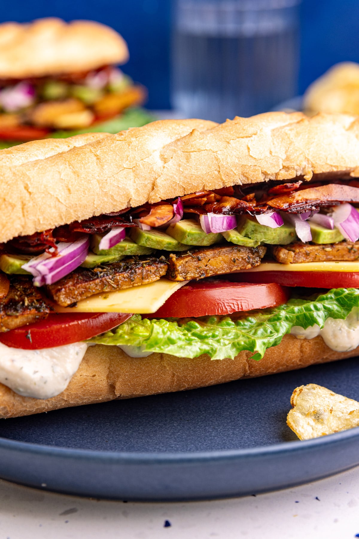 A close up view of the layers of a vegan chicken bacon ranch sandwich.