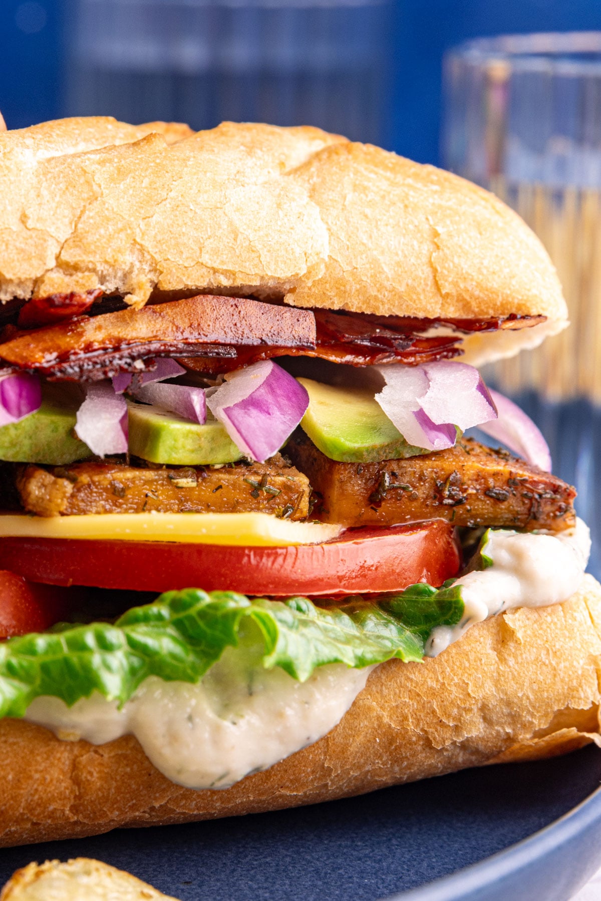 A close up view of the layers of a vegan chicken bacon ranch sandwich.
