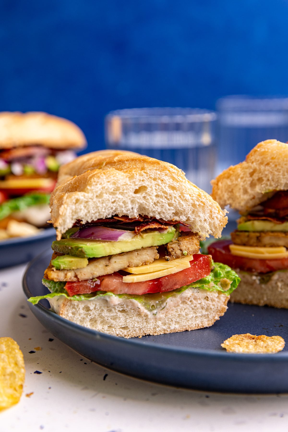 A vegan chicken bacon ranch sandwich, cut in half to see the layers.