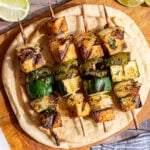 A cutting board with Vegan Grilled Chicken Skewers on top of a pita.