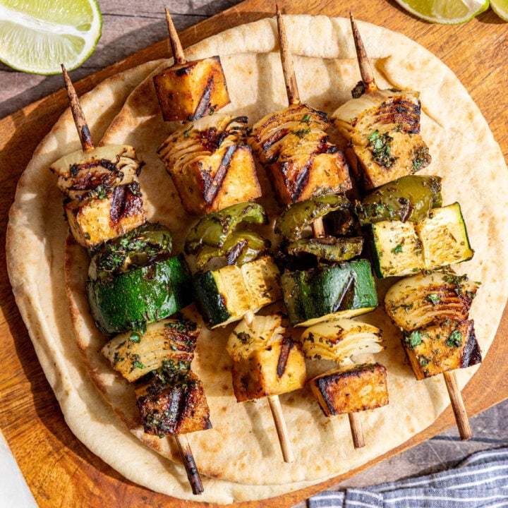 A cutting board with Vegan Grilled Chicken Skewers on top of a pita.