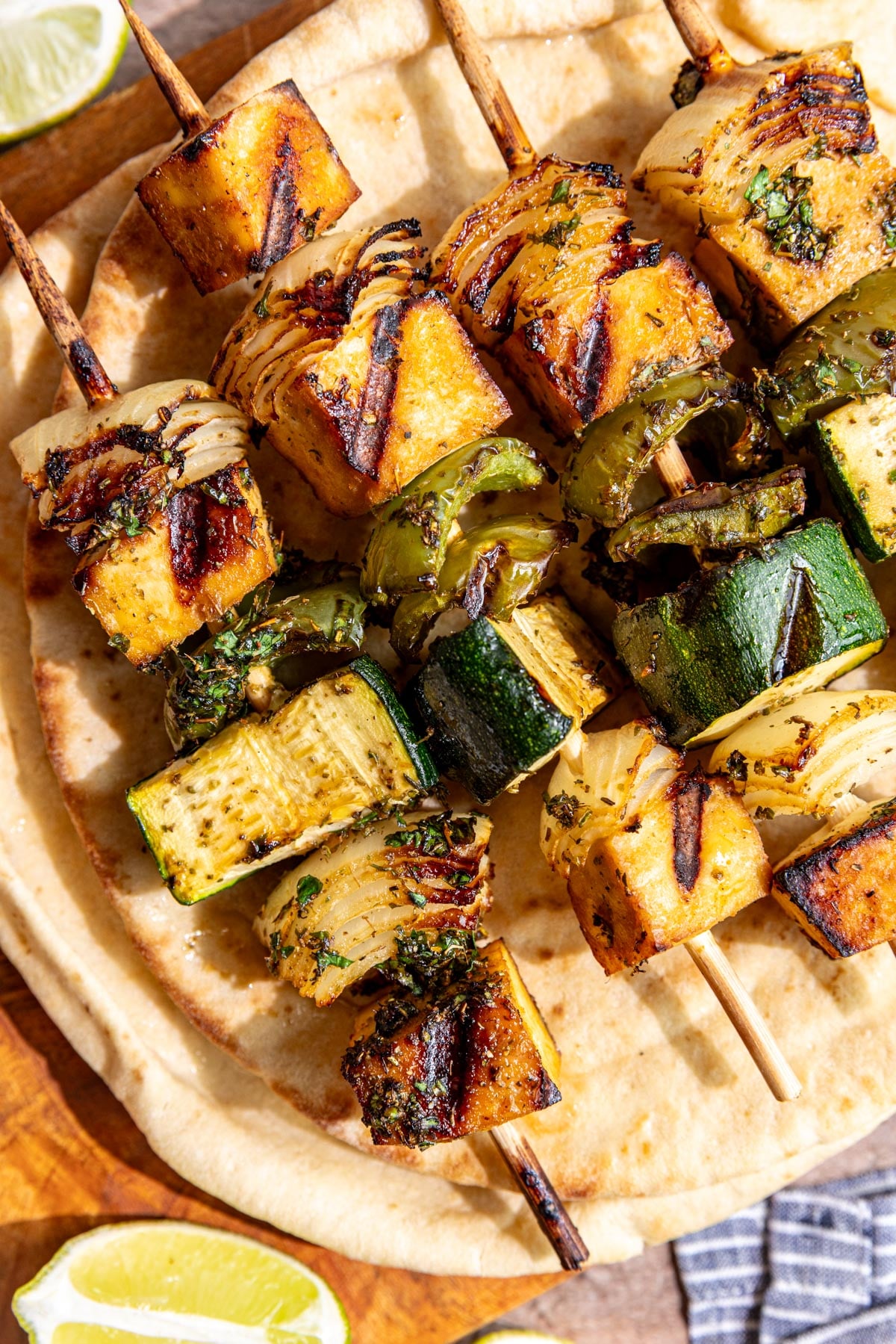 A cutting board with Vegan Grilled Chicken Skewers on top of a pita.