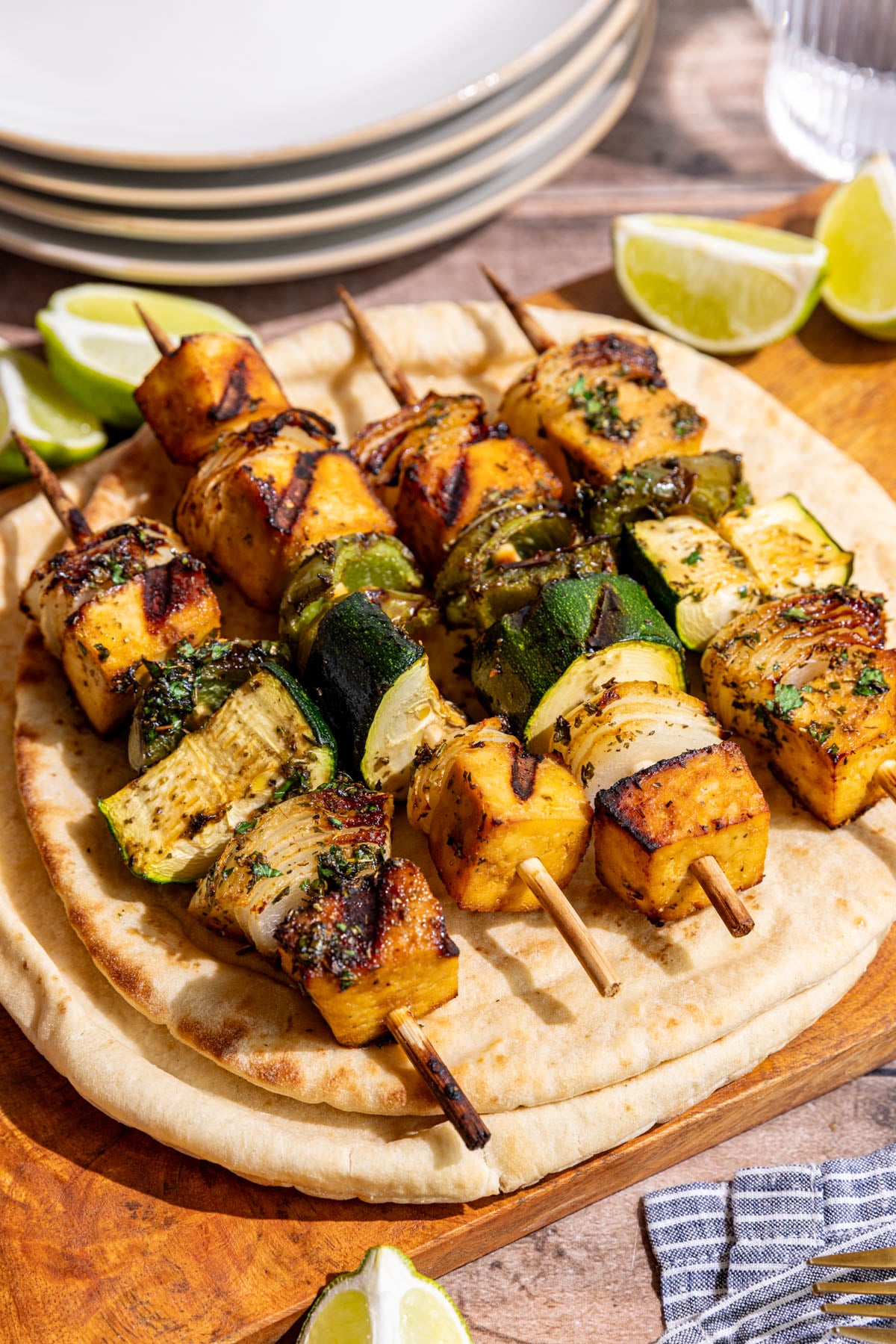 A cutting board with Vegan Grilled Chicken Skewers on top of a pita.