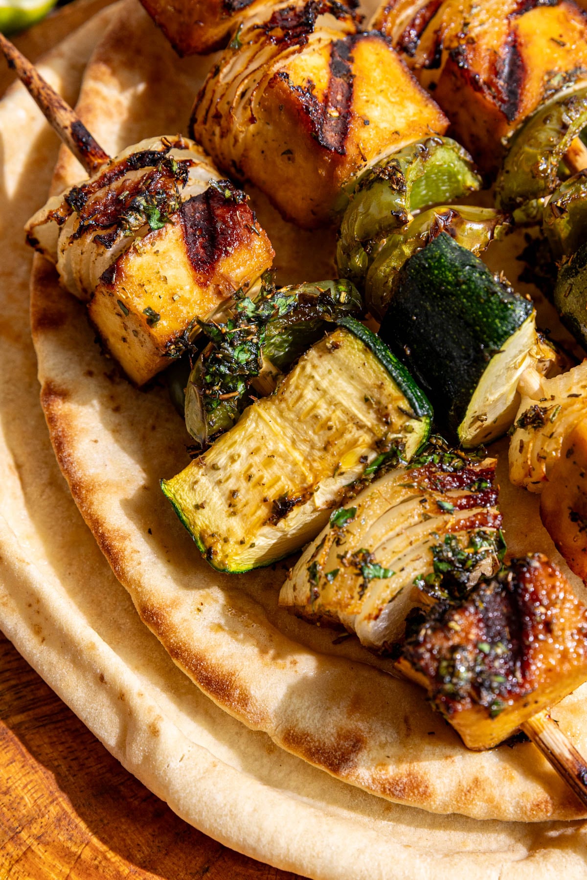 A cutting board with Vegan Grilled Chicken Skewers on top of a pita.