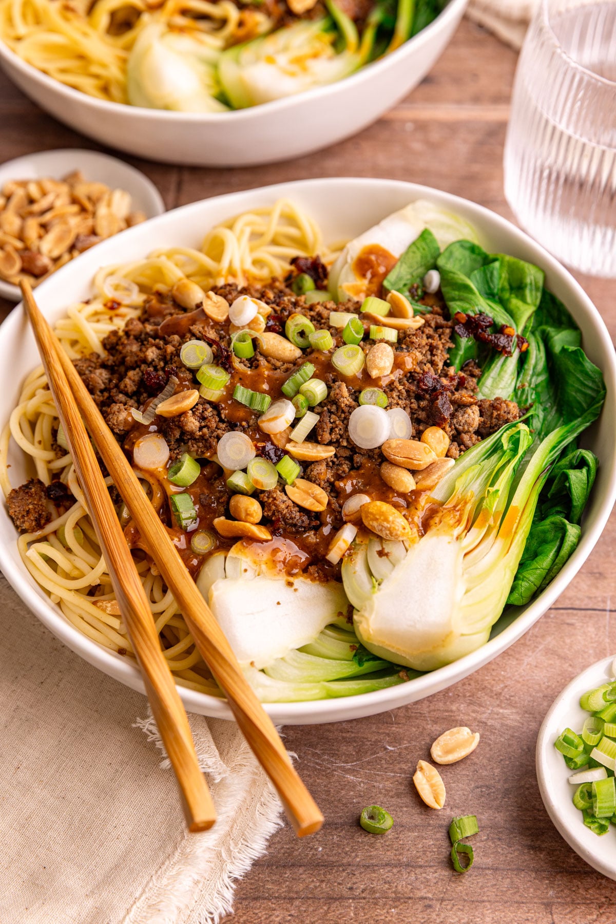 A bowl of Vegan Dan Dan noodles, with a pair of chopsticks, ready to eat.