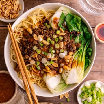 A bowl of Vegan Dan Dan noodles, with a pair of chopsticks, ready to eat.