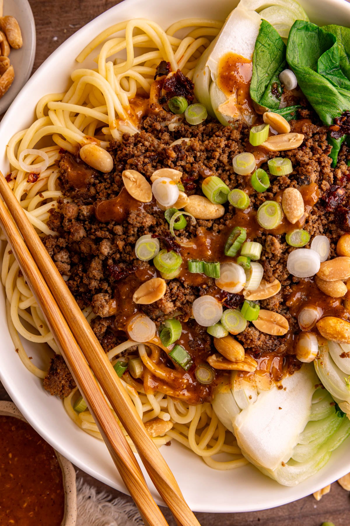 A bowl of Vegan Dan Dan noodles, with a pair of chopsticks, ready to eat.