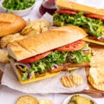 A vegan deli turkey sandwich on a baguette, with potato chips.