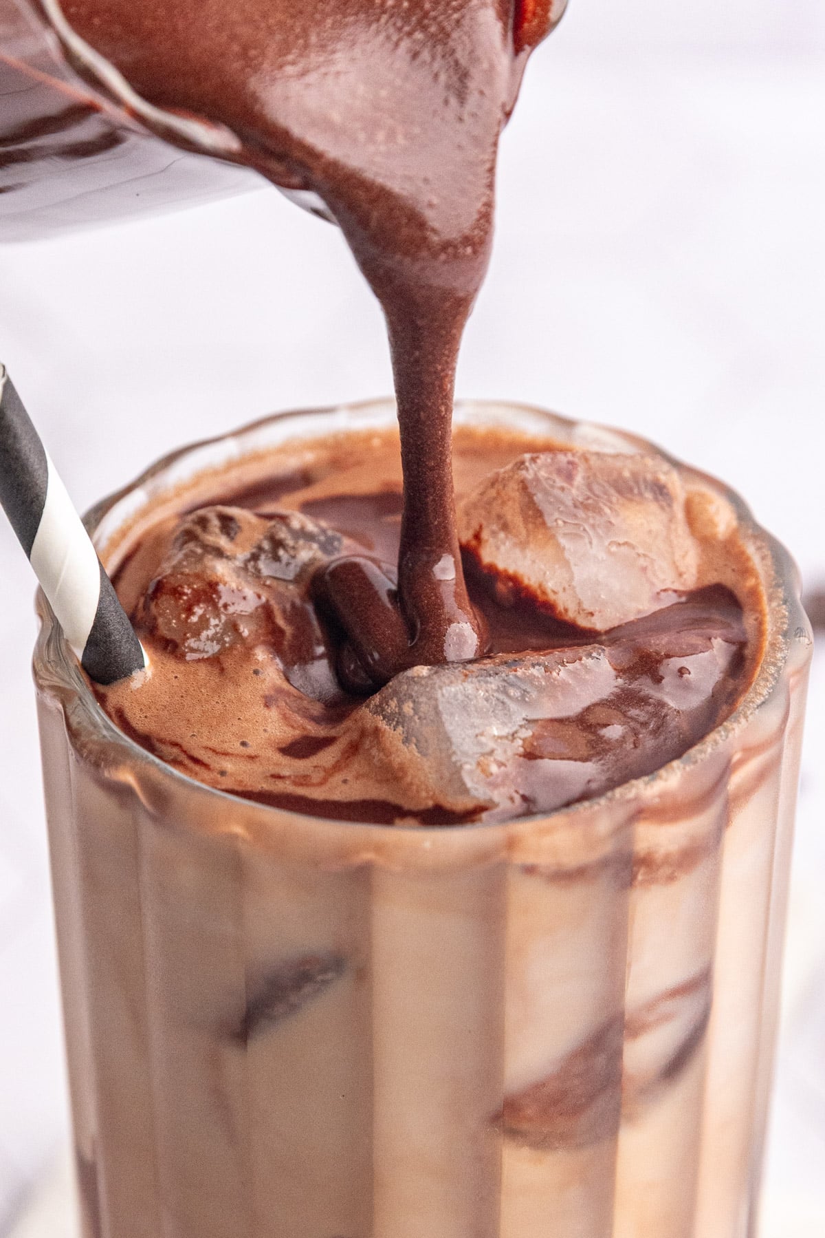 Vegan chocolate syrup being poured onto a vegan iced mocha.