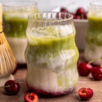 A cherry matcha latte with layers of syrup, oat milk, and matcha.