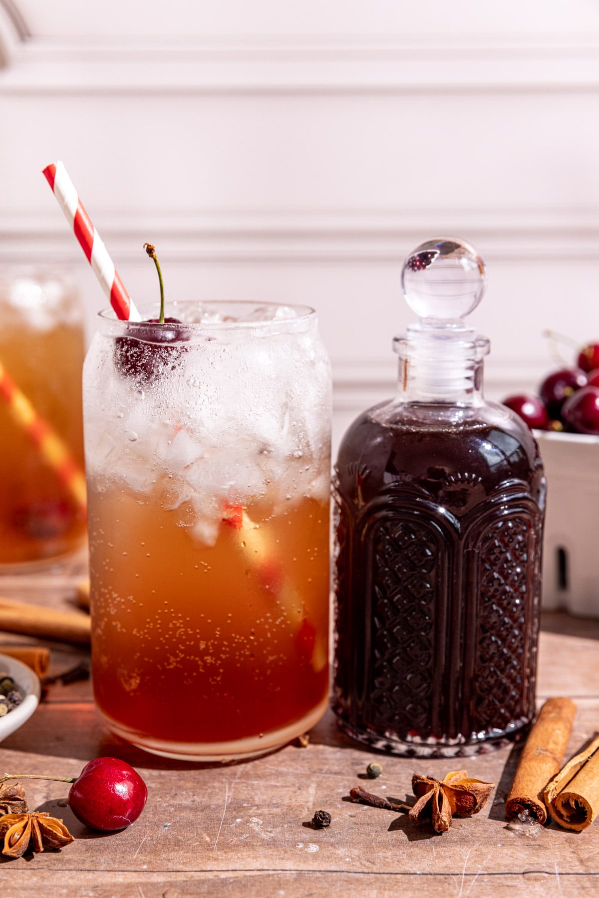 A soda glass of homemade Dr. Pepper with a jar of Dr. Pepper syrup.