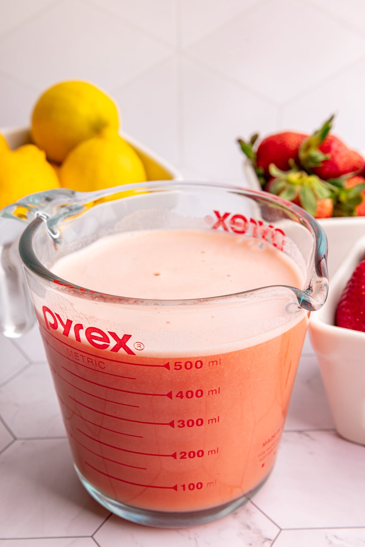 A pyrex glass of strawberry lemon ginger wellness shots.
