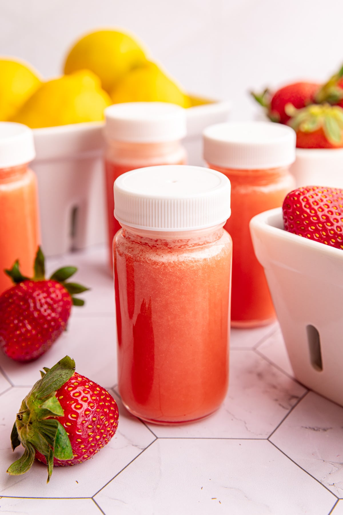 A small juice shot glass of strawberry lemon ginger wellness shots.