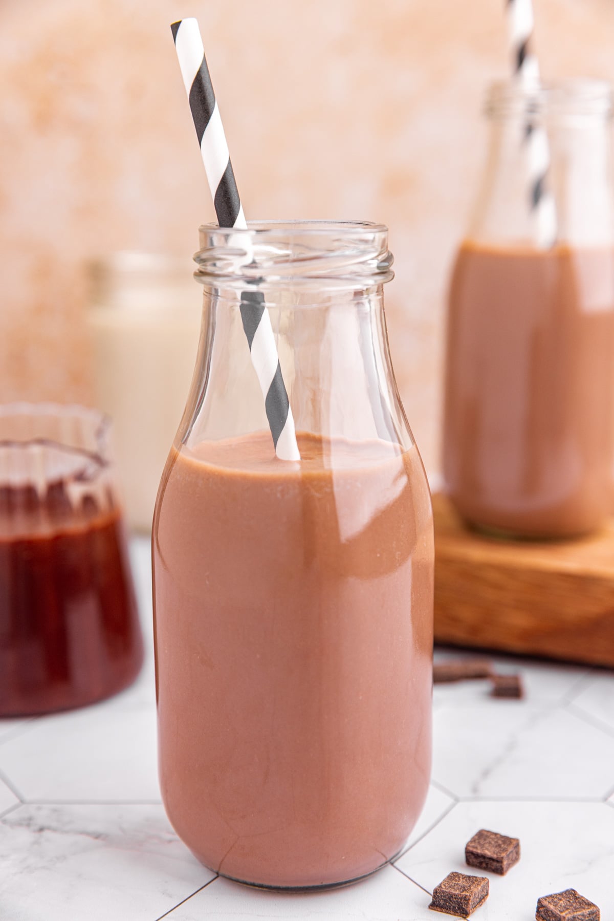 A milk bottle of chocolate milk with a black and white striped straw.