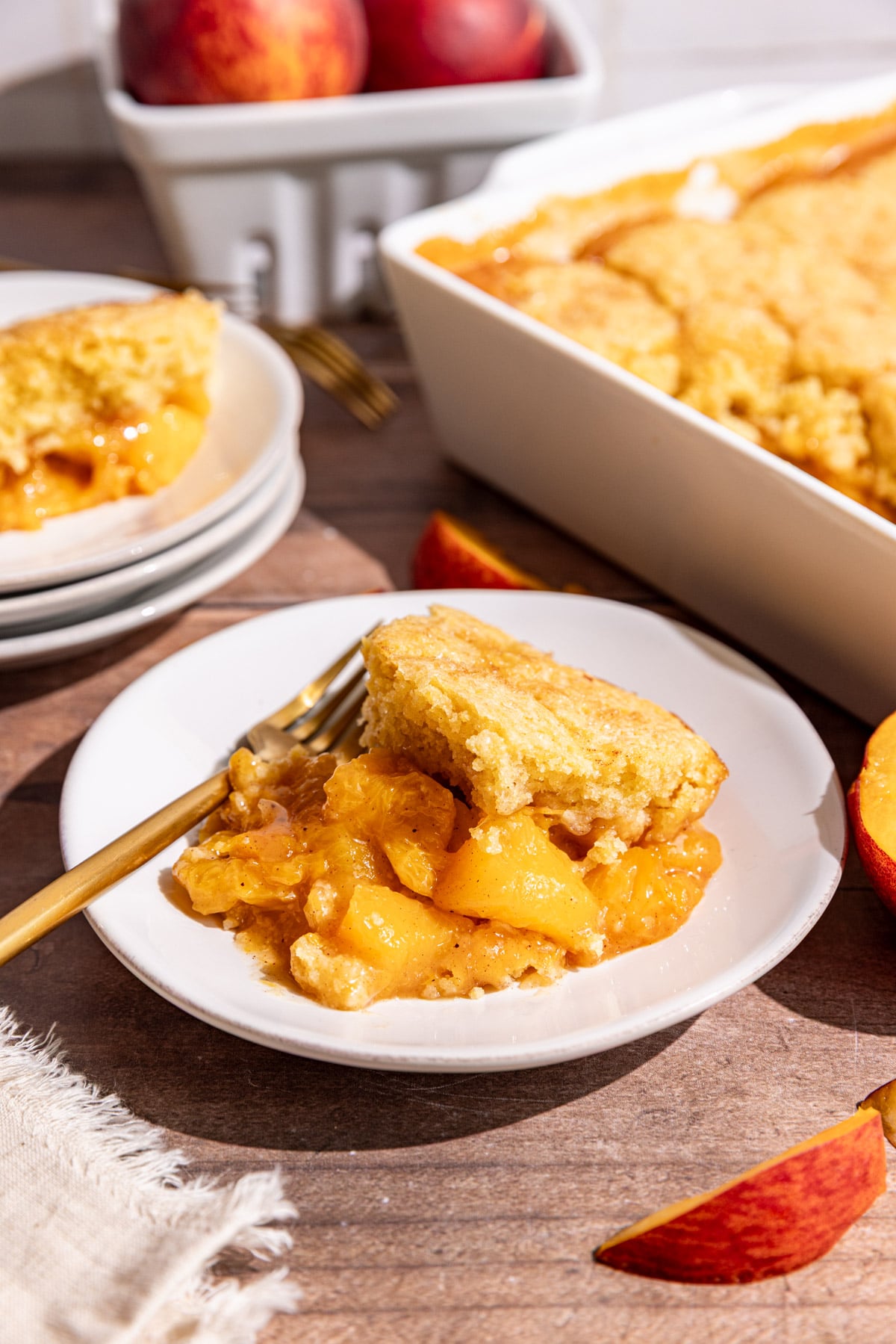 A serving of vegan cornmeal peach cobbler on a plate with a fork.