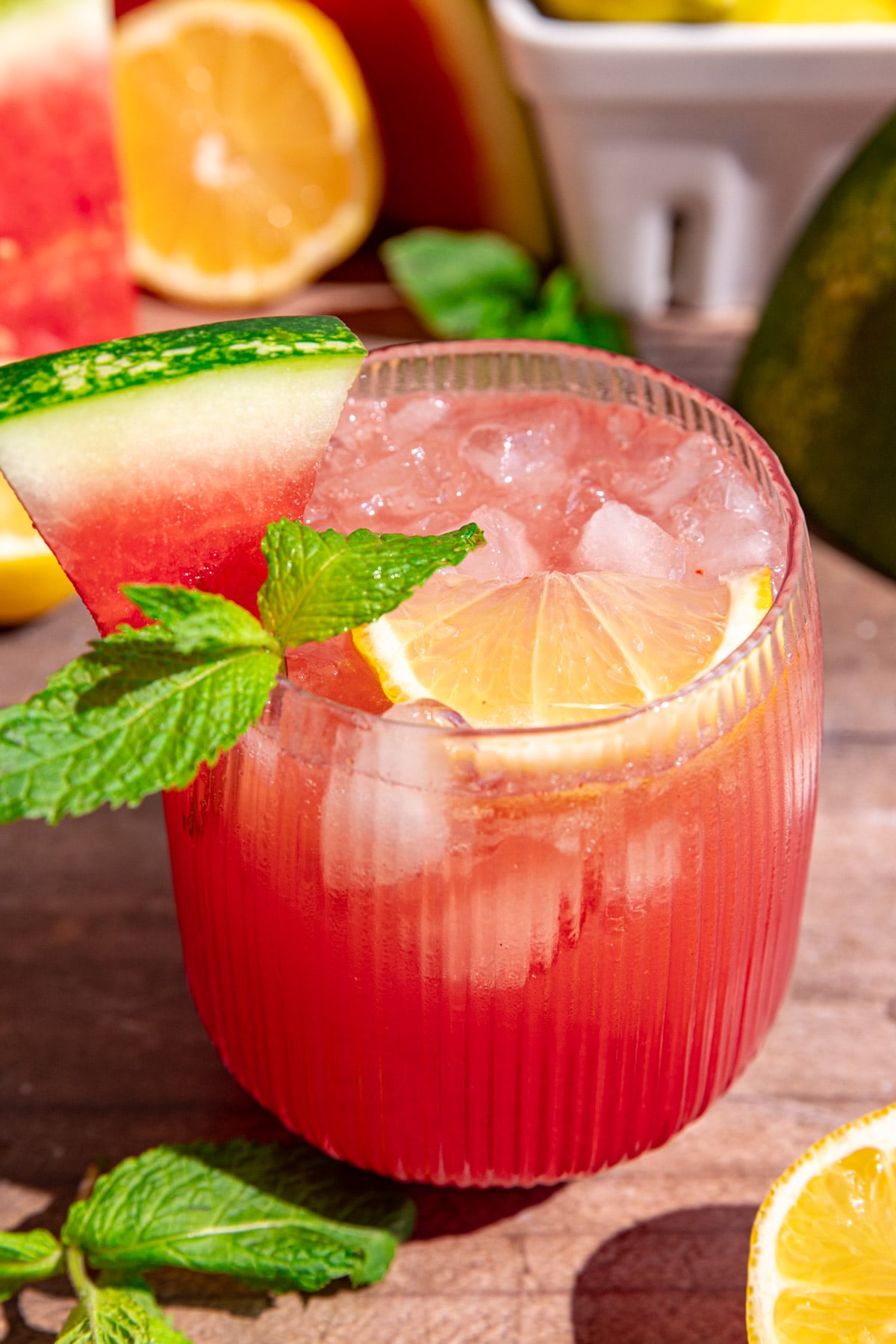 A glass of watermelon lemonade garnished with lemon, mint, and watermelon.