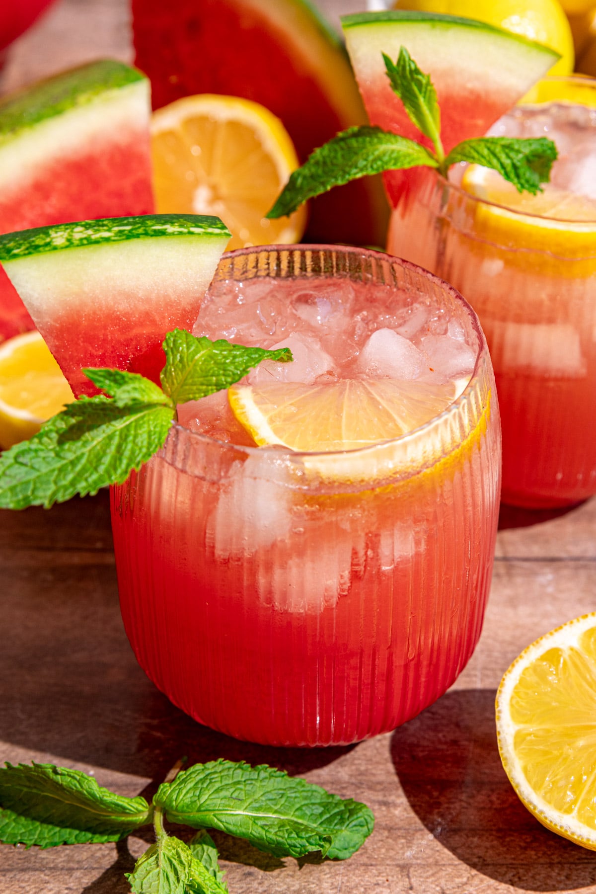 A glass of watermelon lemonade garnished with lemon, mint, and watermelon.