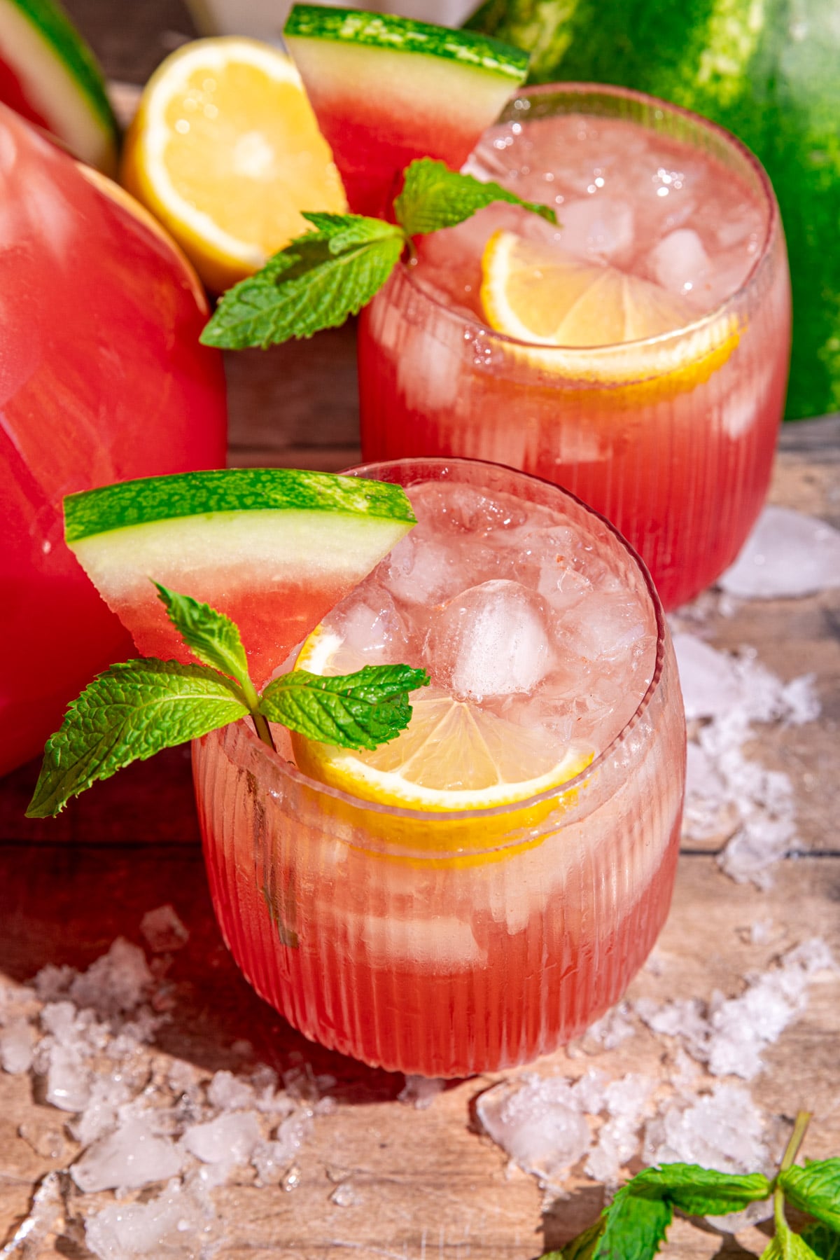 A glass of watermelon lemonade garnished with lemon, mint, and watermelon.