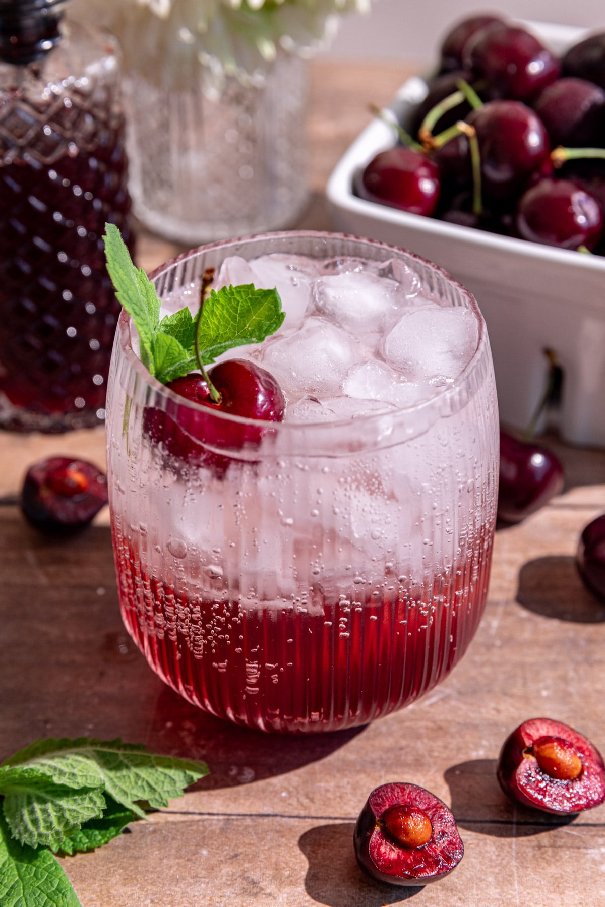 A cherry shrub mocktail garnished with a cherry and mint.