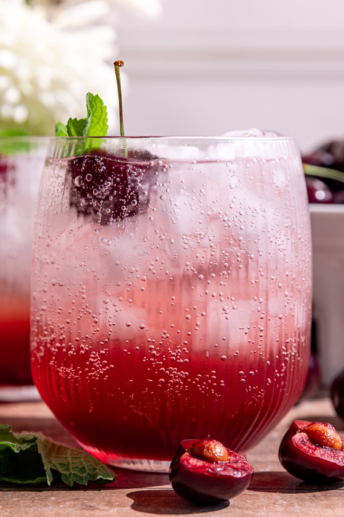 A cherry shrub mocktail garnished with a cherry and mint.