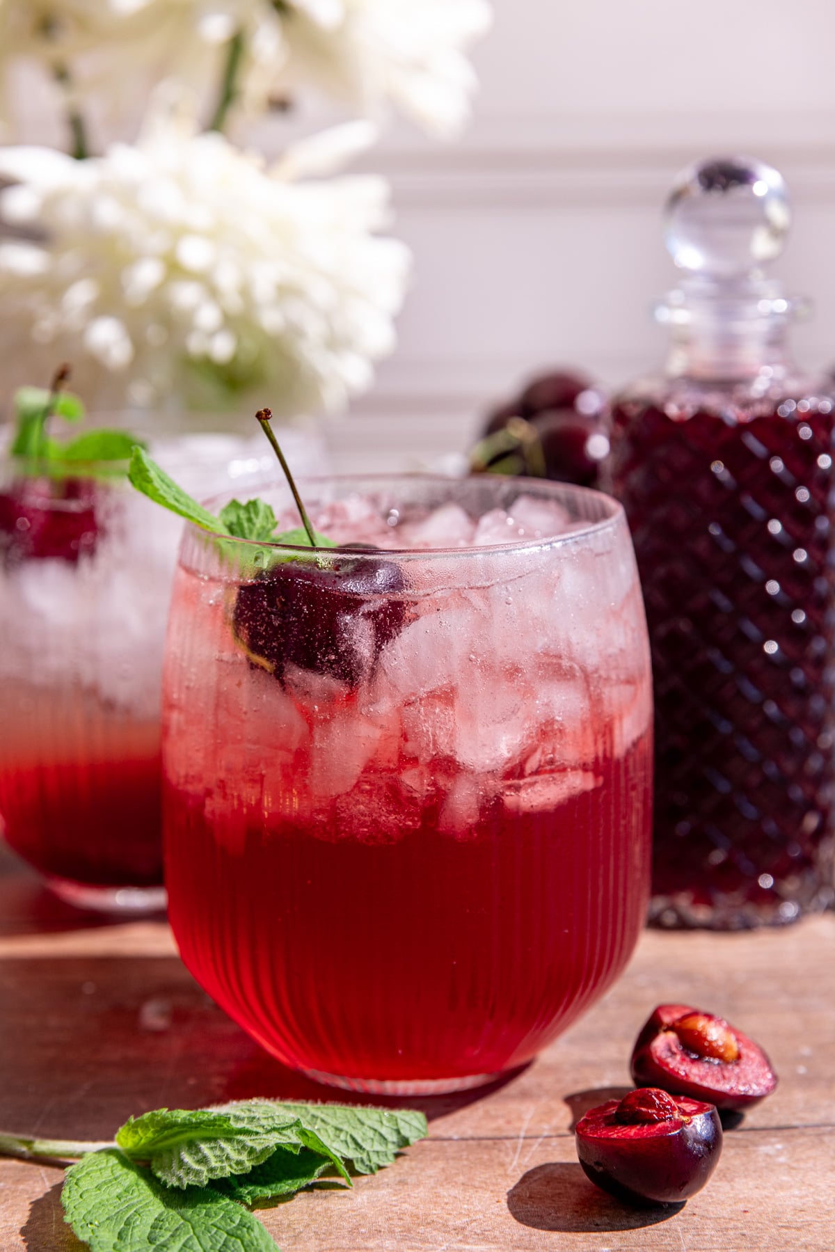 A cherry shrub mocktail garnished with a cherry and mint.