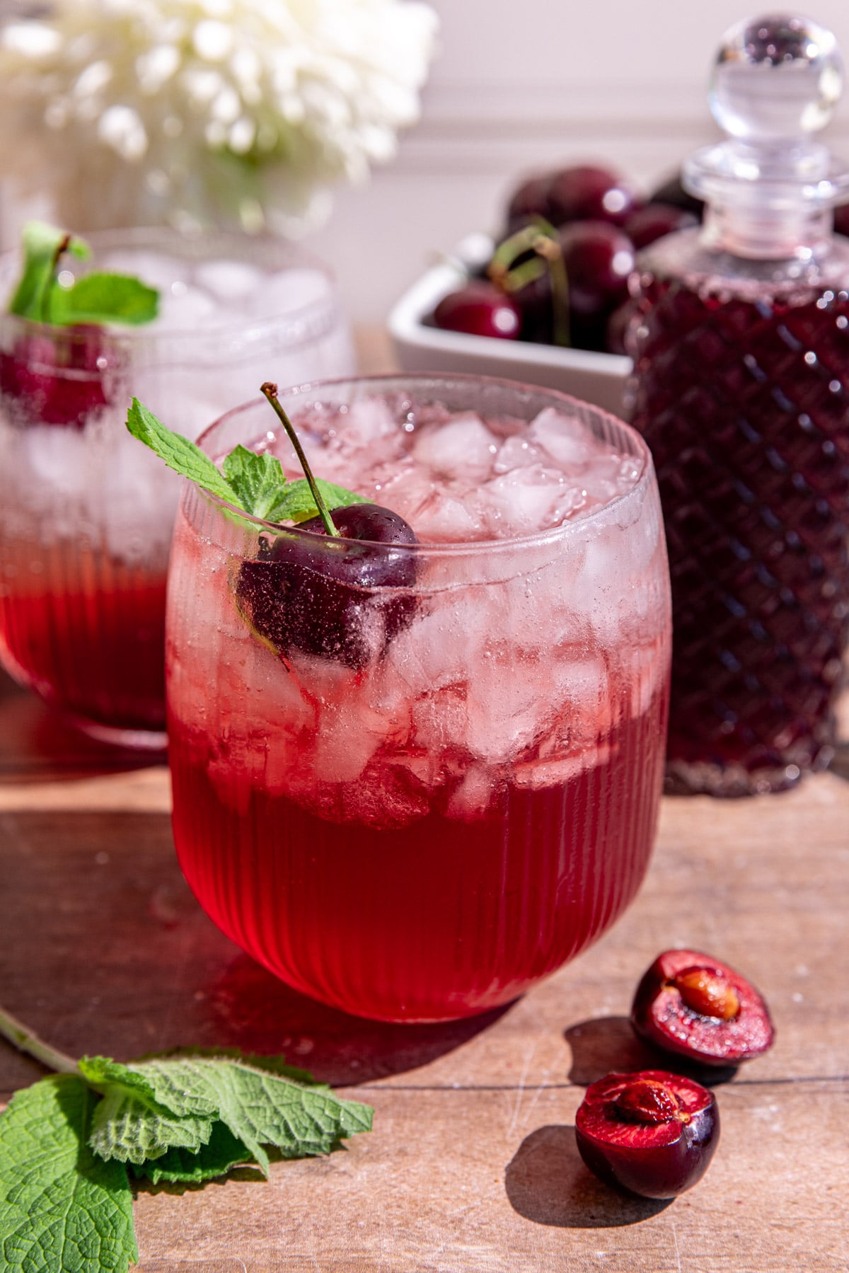 A cherry shrub mocktail garnished with a cherry and mint.
