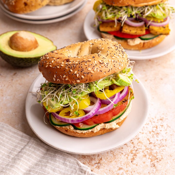 A hummus bagel sandwich on a plate ready to eat.