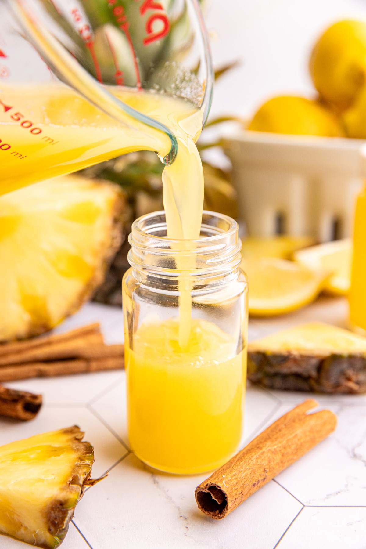 A pineapple cinnamon wellness shot being poured into a juice shot bottle.