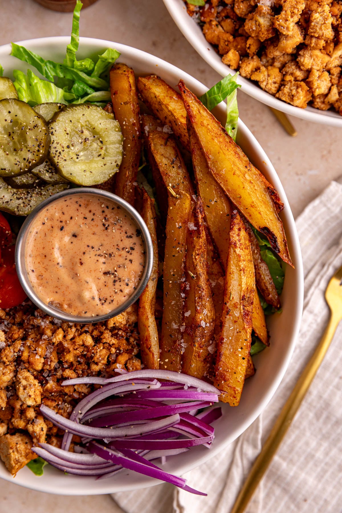 A close up view of the fries in a vegan burger bowl.