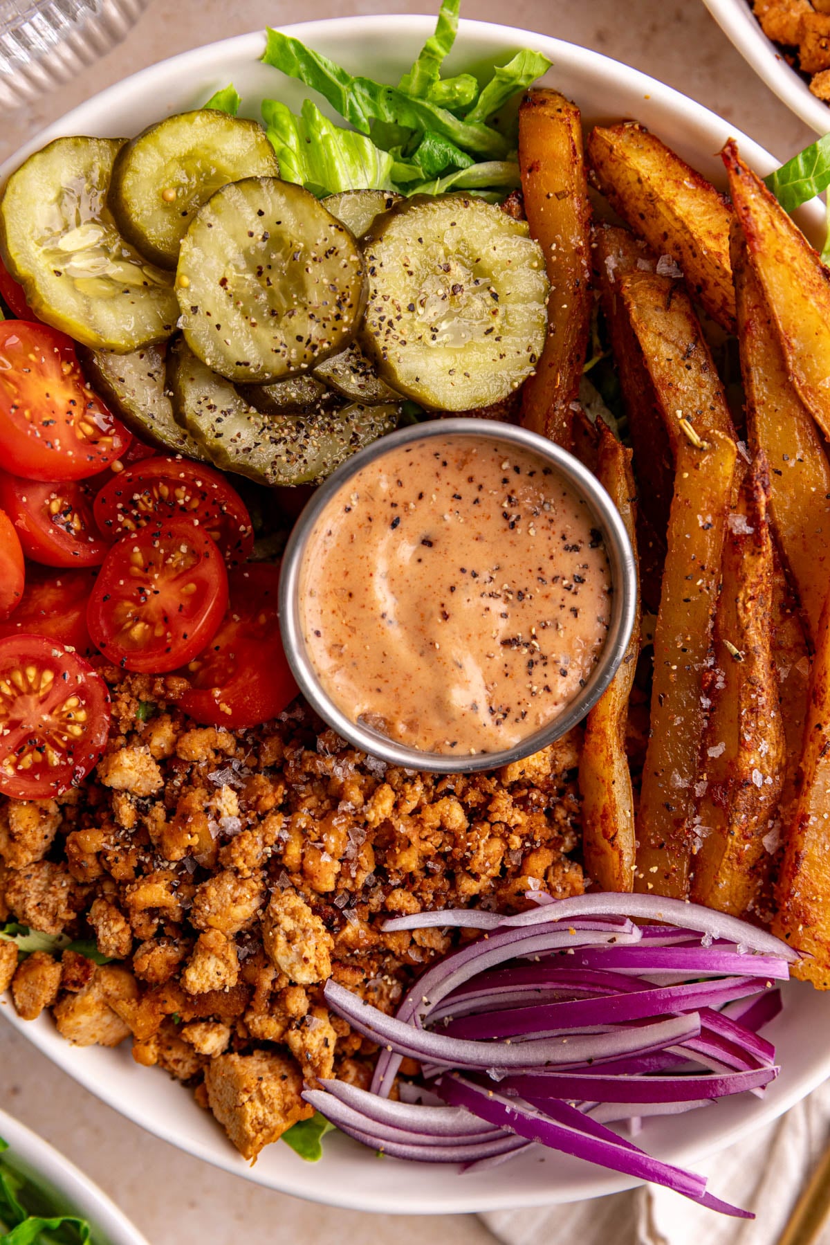 A close up view of a vegan burger bowl, with a condiment dish of sauce.