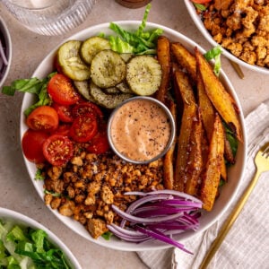 A vegan burger bowl, with a napkin and fork, ready to eat.