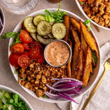 A vegan burger bowl, with a napkin and fork, ready to eat.