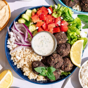 A vegan Greek couscous bowl with vegan meatballs, veggies, and vegan tzatziki.