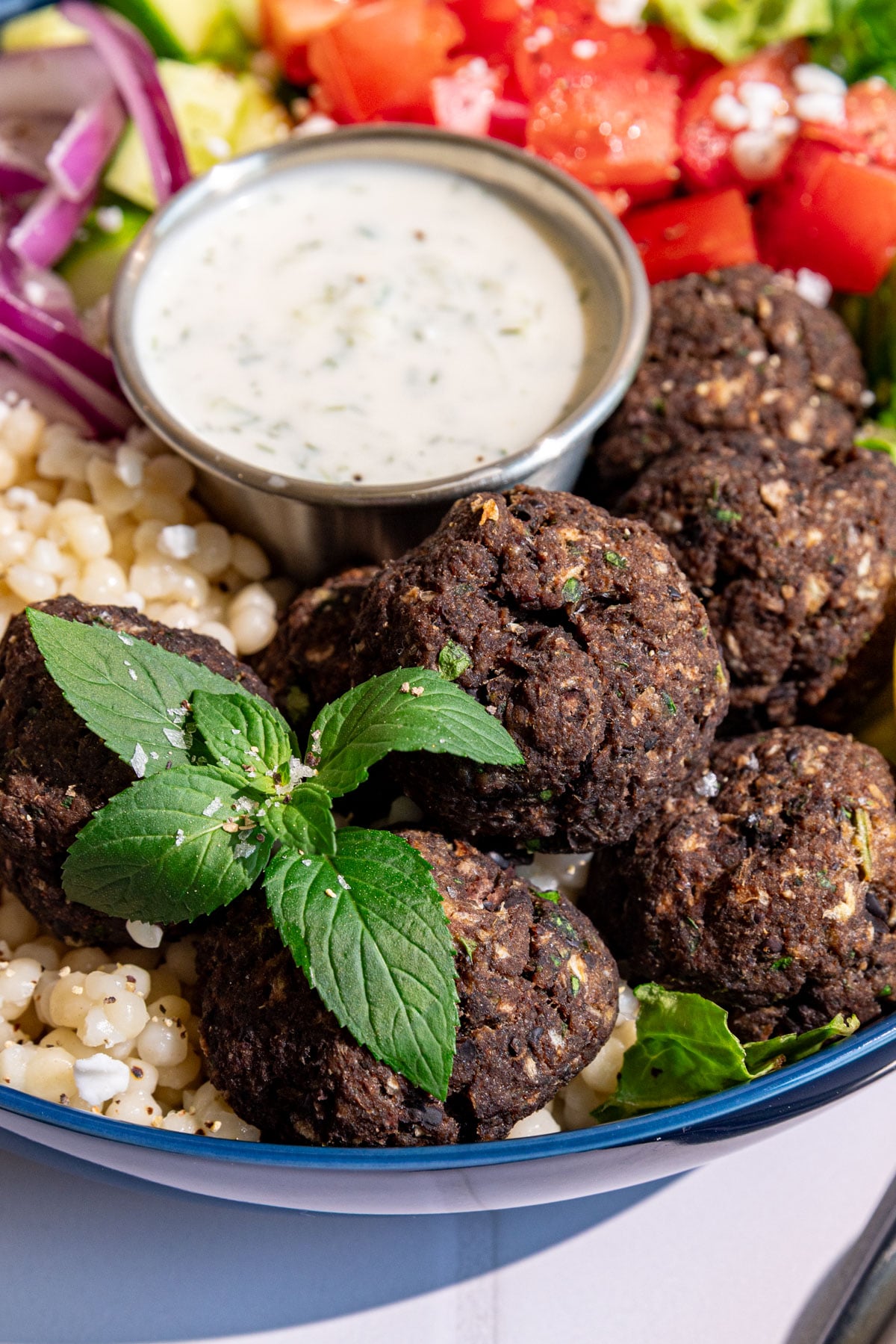 A close up view of the Greek meatballs in a vegan Greek couscous bowl.