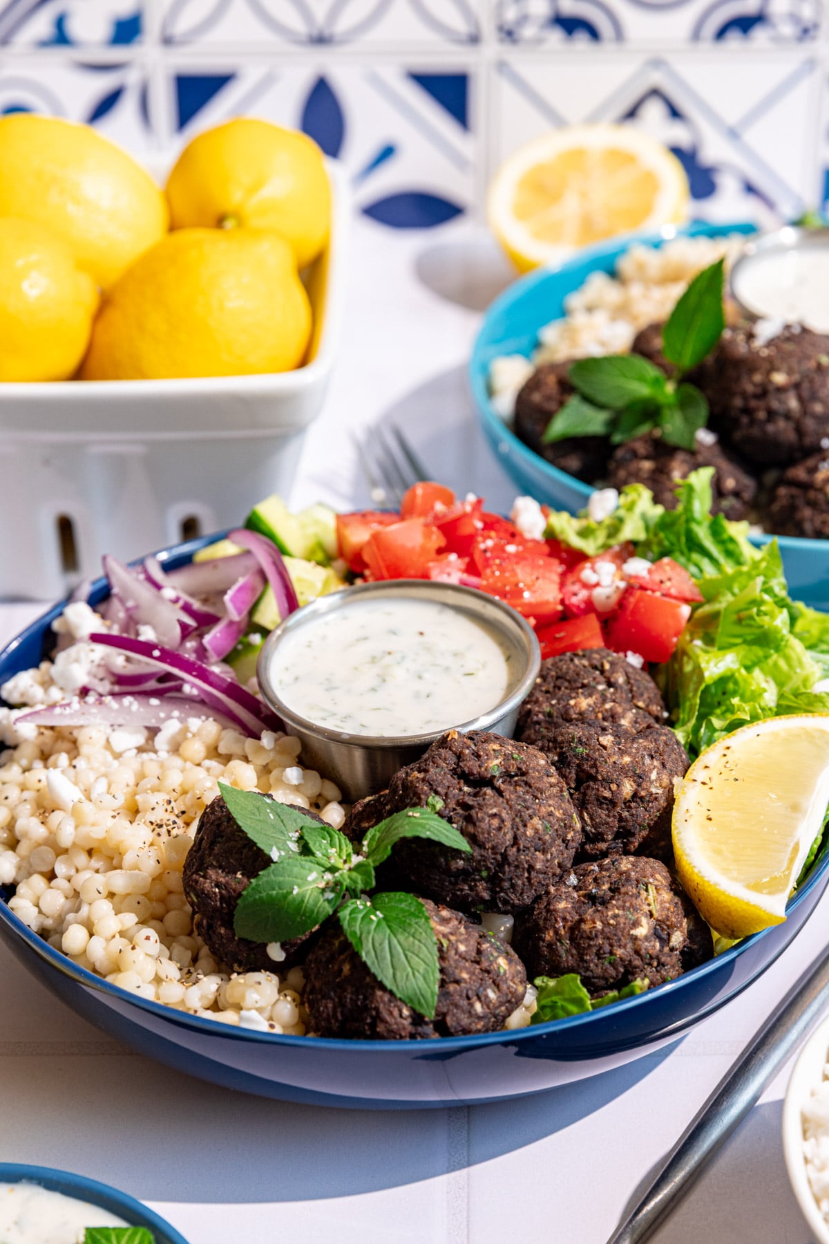 A vegan Greek couscous bowl with vegan meatballs, veggies, and vegan tzatziki.