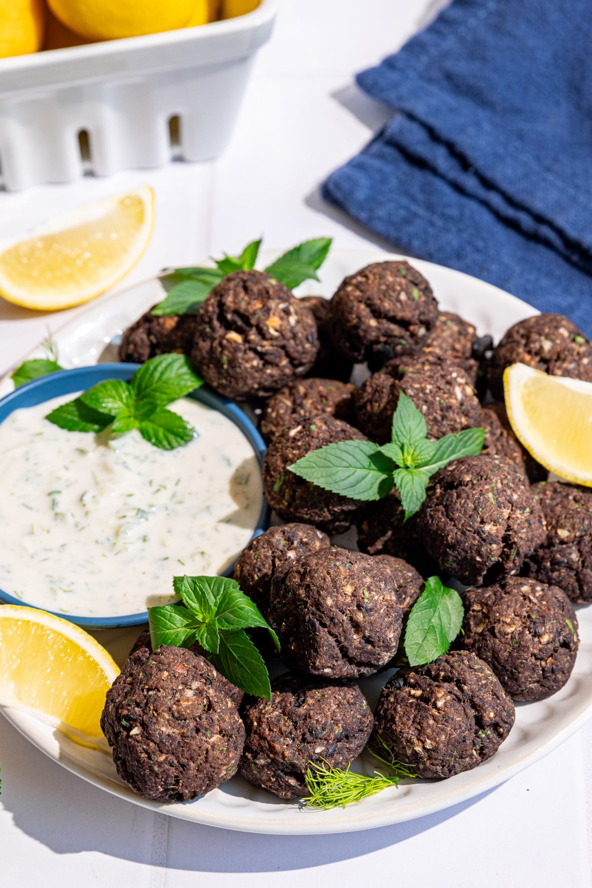 A plate of vegan Greek meatballs, garnished with fresh mint, served with tzatziki.