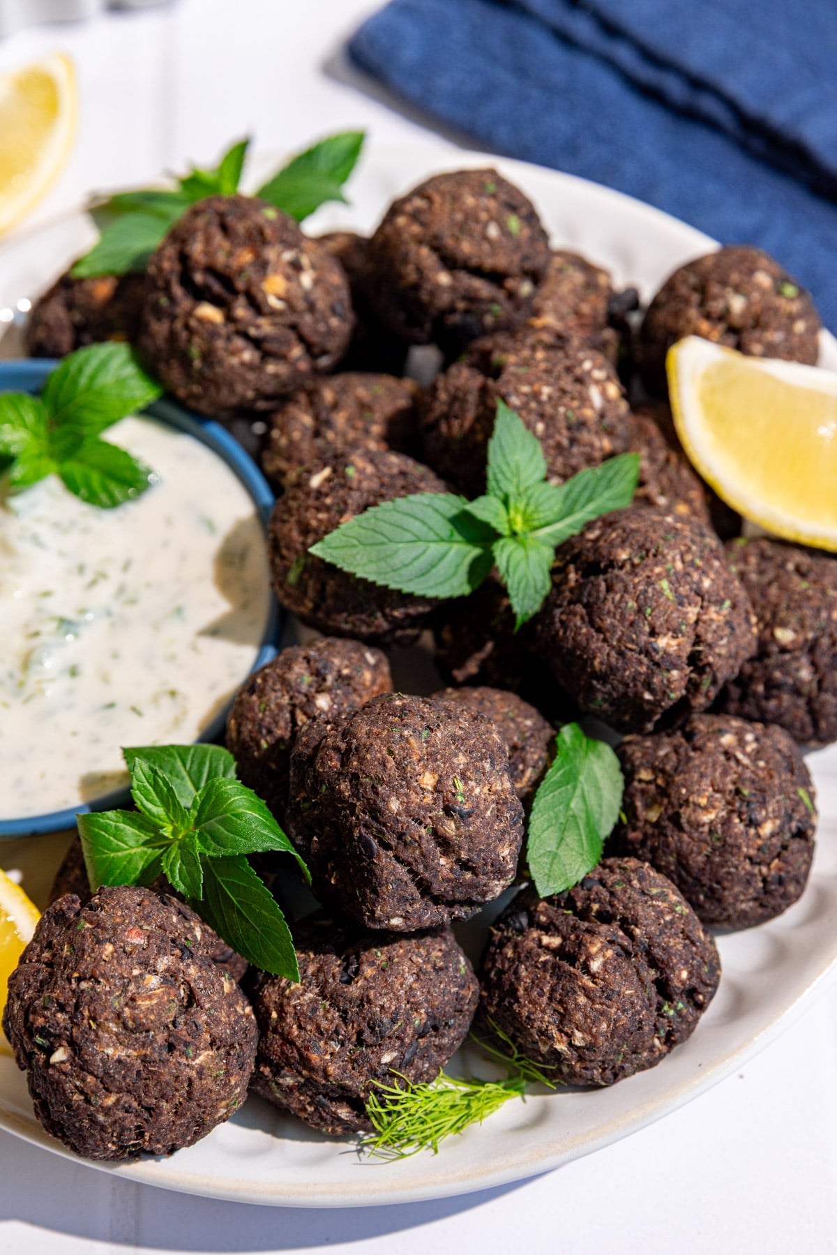 A plate of vegan Greek meatballs, garnished with fresh mint, served with tzatziki.