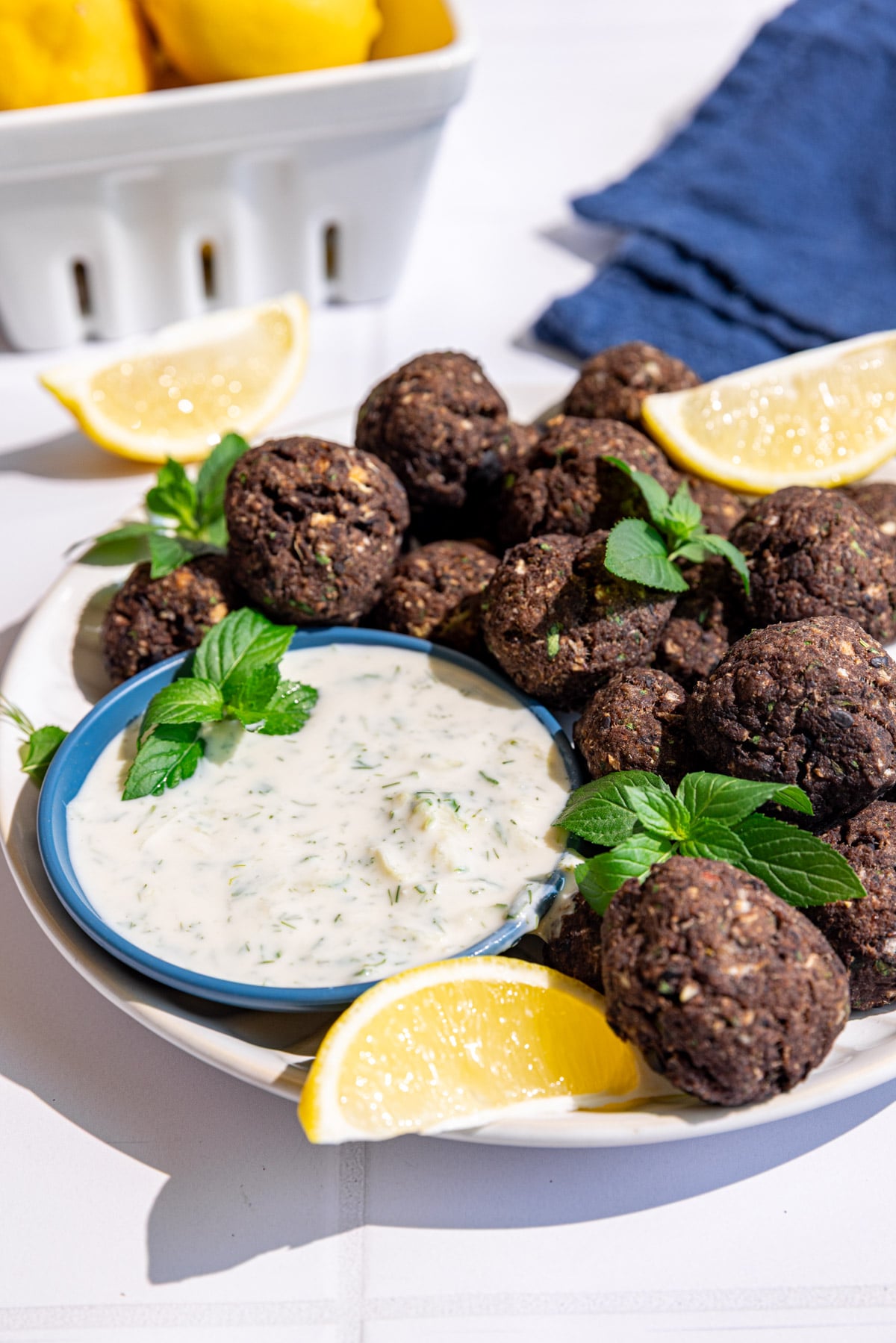 A plate of vegan Greek meatballs, garnished with fresh mint, served with tzatziki.