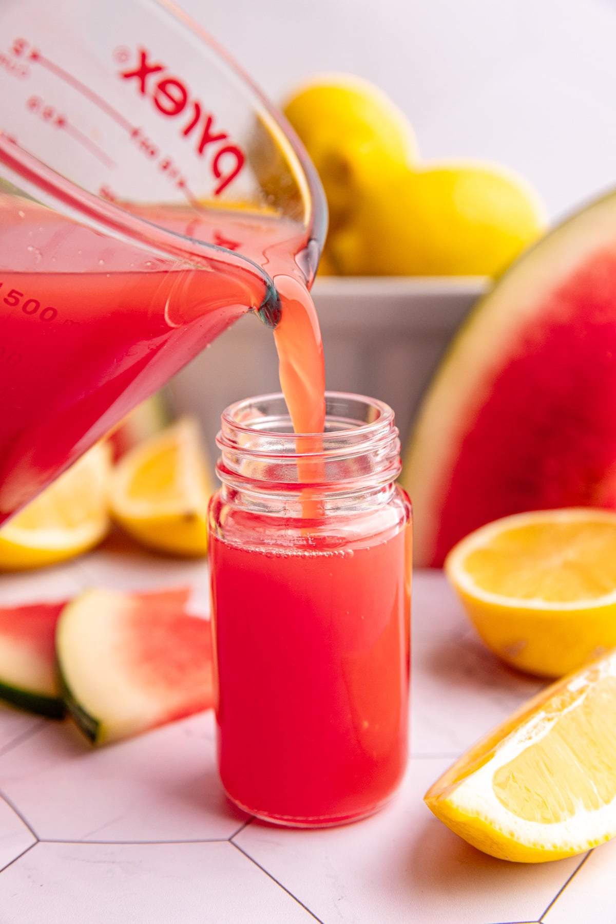 Watermelon ginger juice being poured into a juice shot glass.