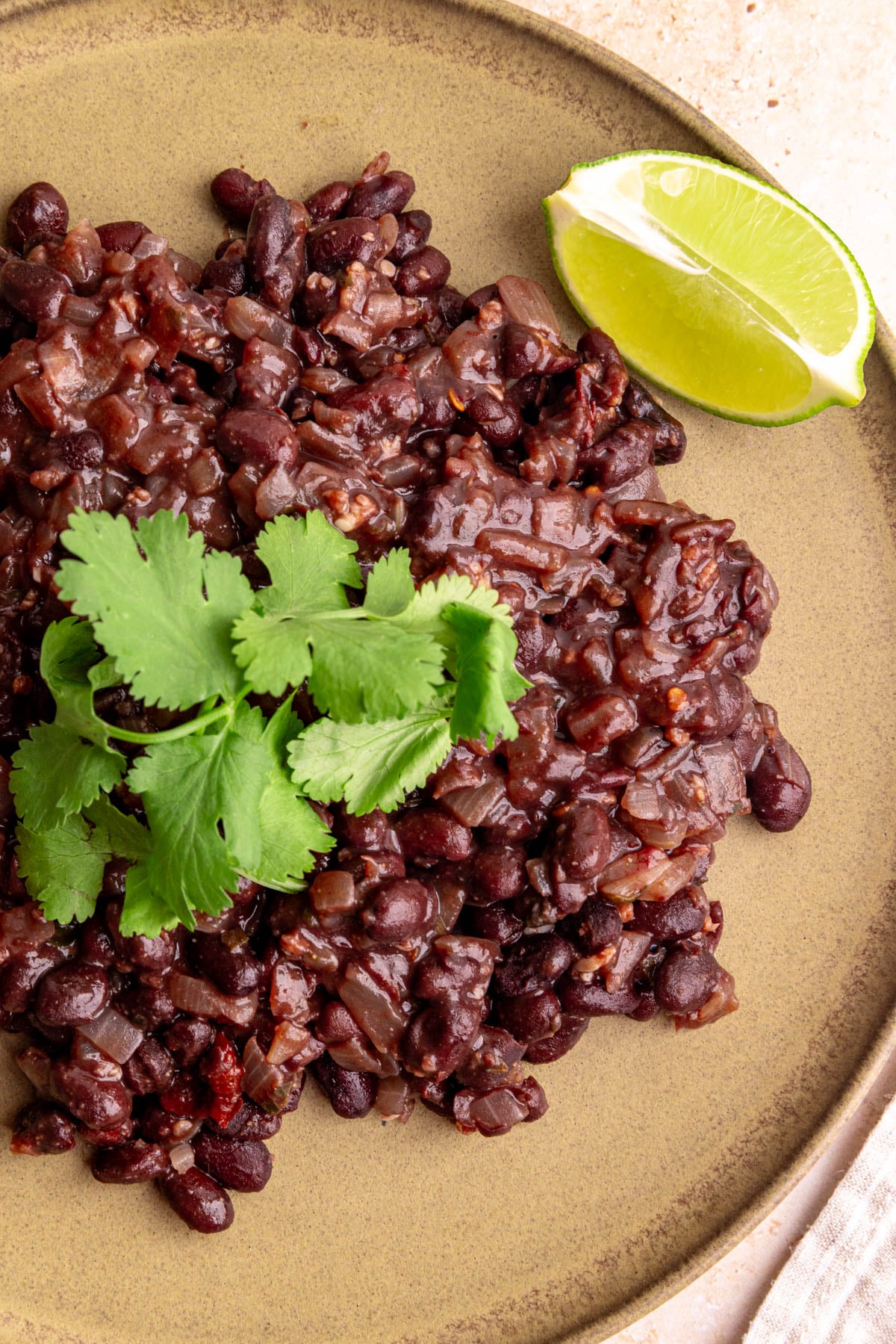A plate of homemade chipotle style black beans, garnished with fresh cilantro.