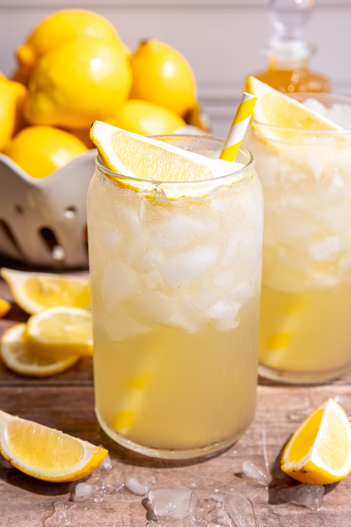 Two glasses of lemon cream soda, garnished with a lemon wedge and yellow striped straw.