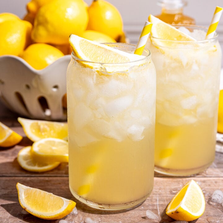 Two glasses of lemon cream soda, garnished with a lemon wedge and yellow striped straw.