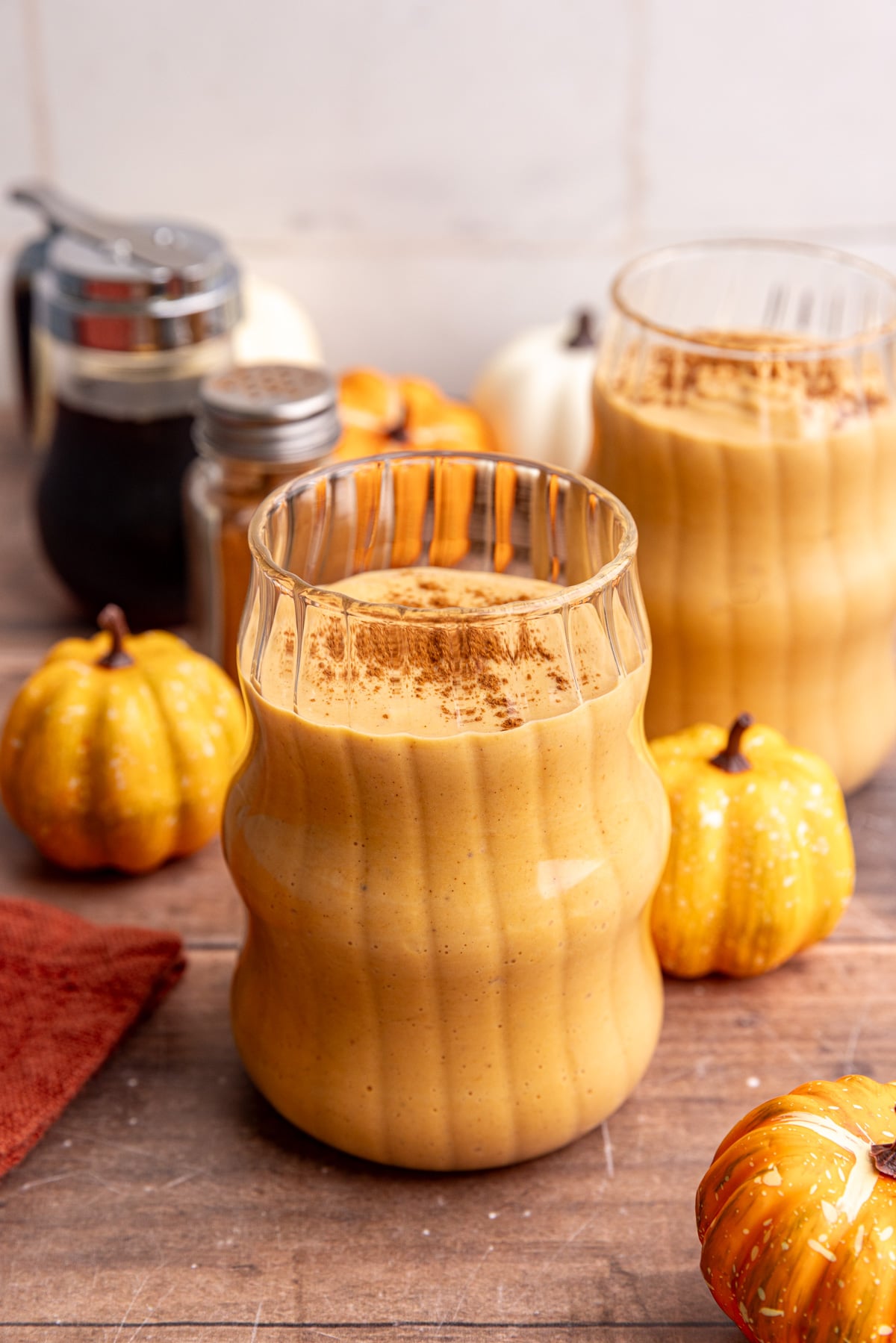 A pumpkin banana smoothie in a glass, topped with cinnamon.