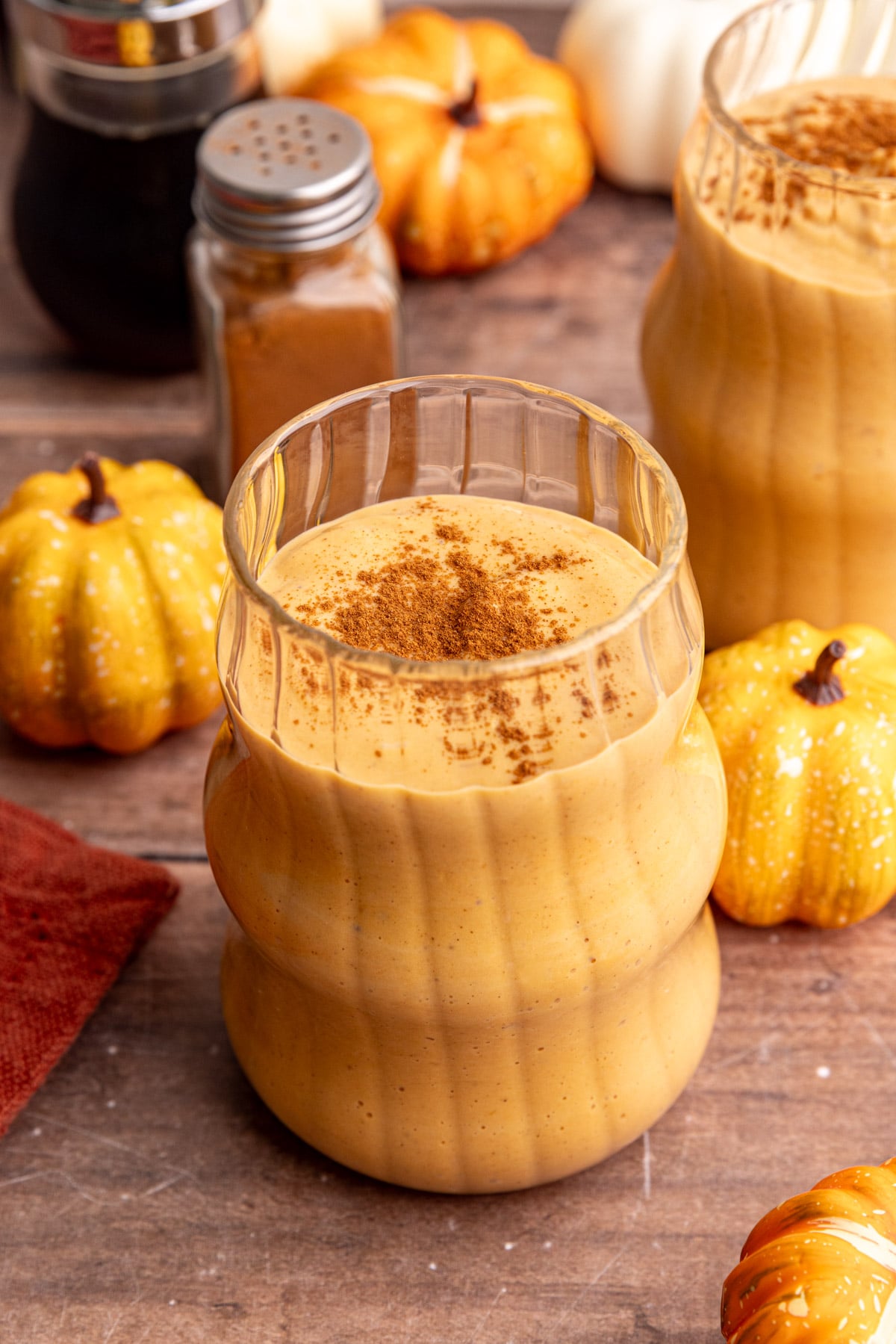 A pumpkin banana smoothie in a glass, topped with cinnamon.