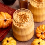A pumpkin banana smoothie in a glass, topped with cinnamon.