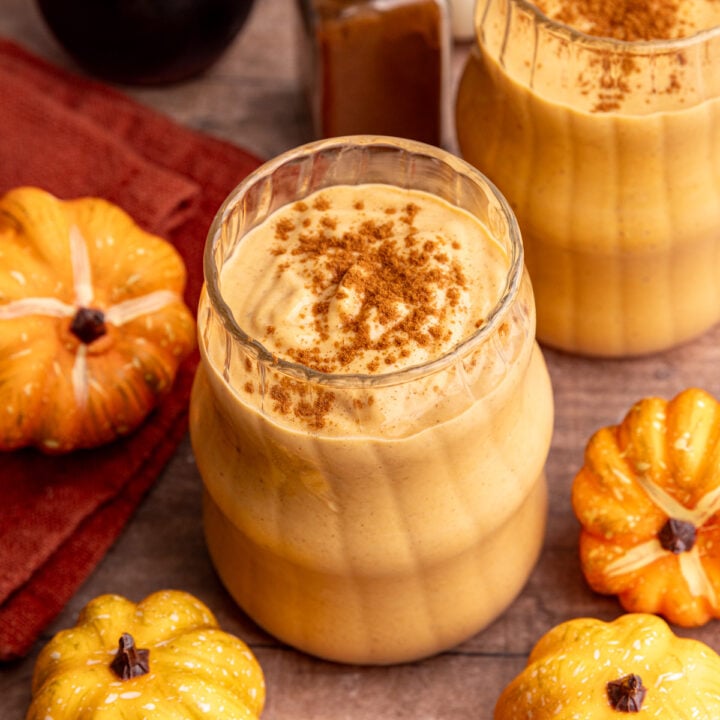 A pumpkin banana smoothie in a glass, topped with cinnamon.