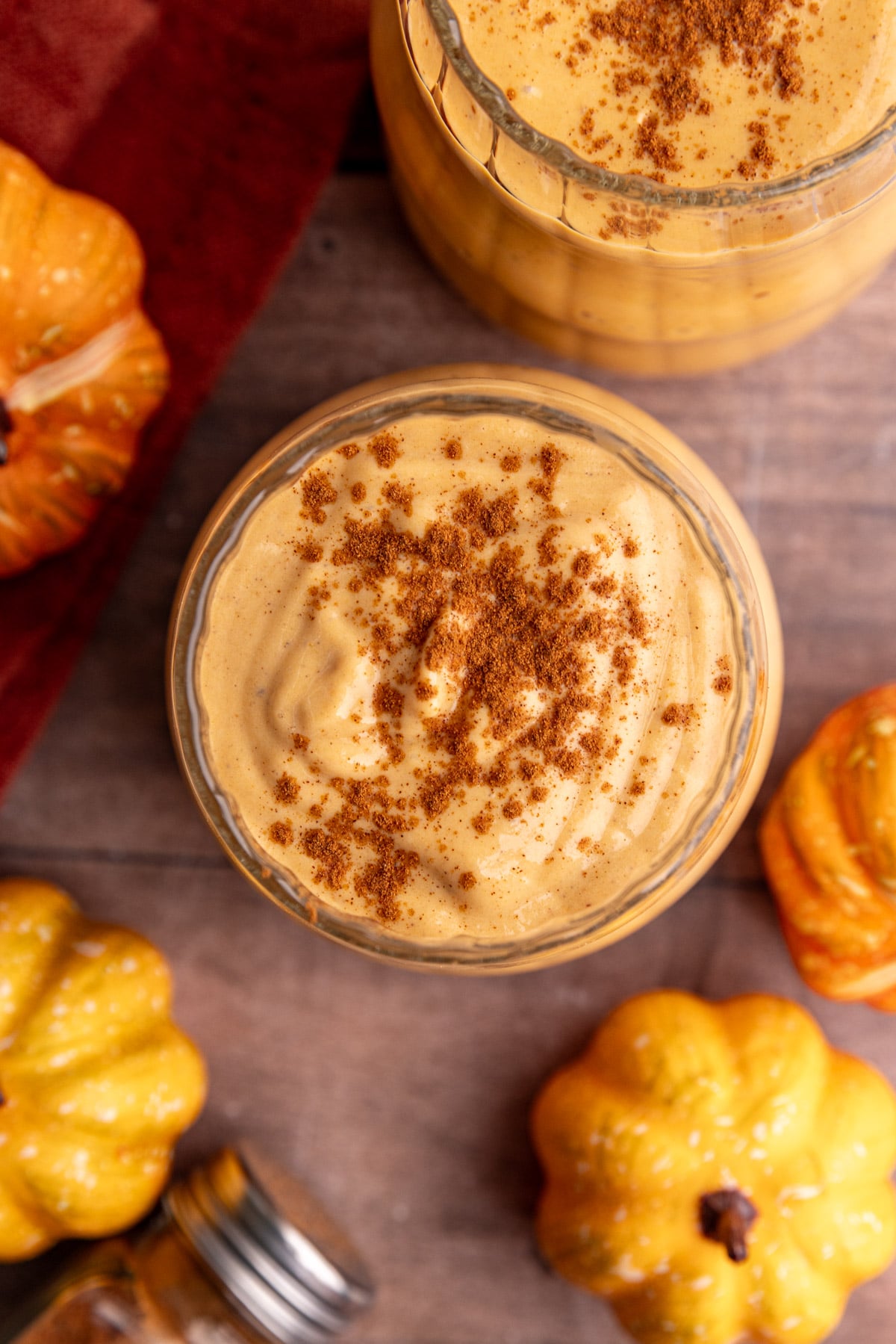 A pumpkin banana smoothie in a glass, topped with cinnamon.