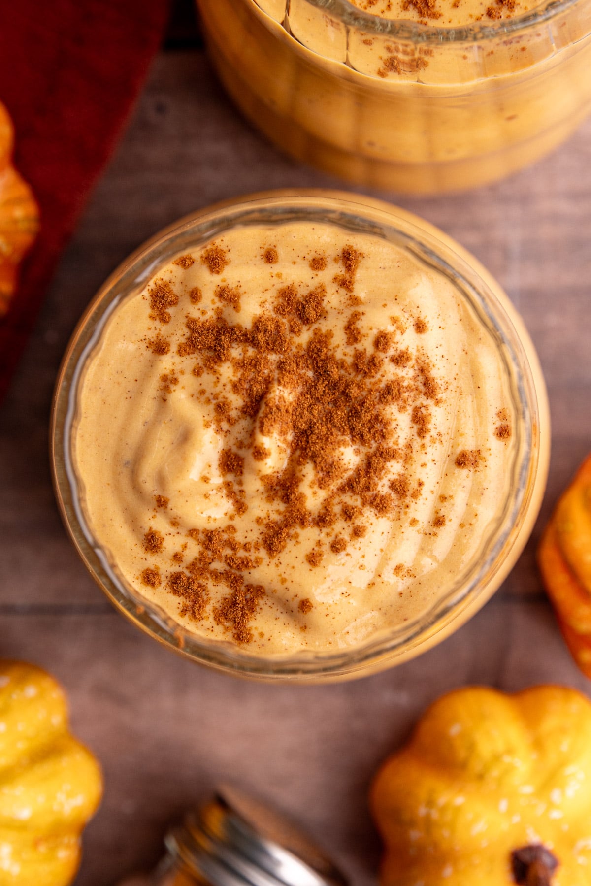 A pumpkin banana smoothie in a glass, topped with cinnamon.