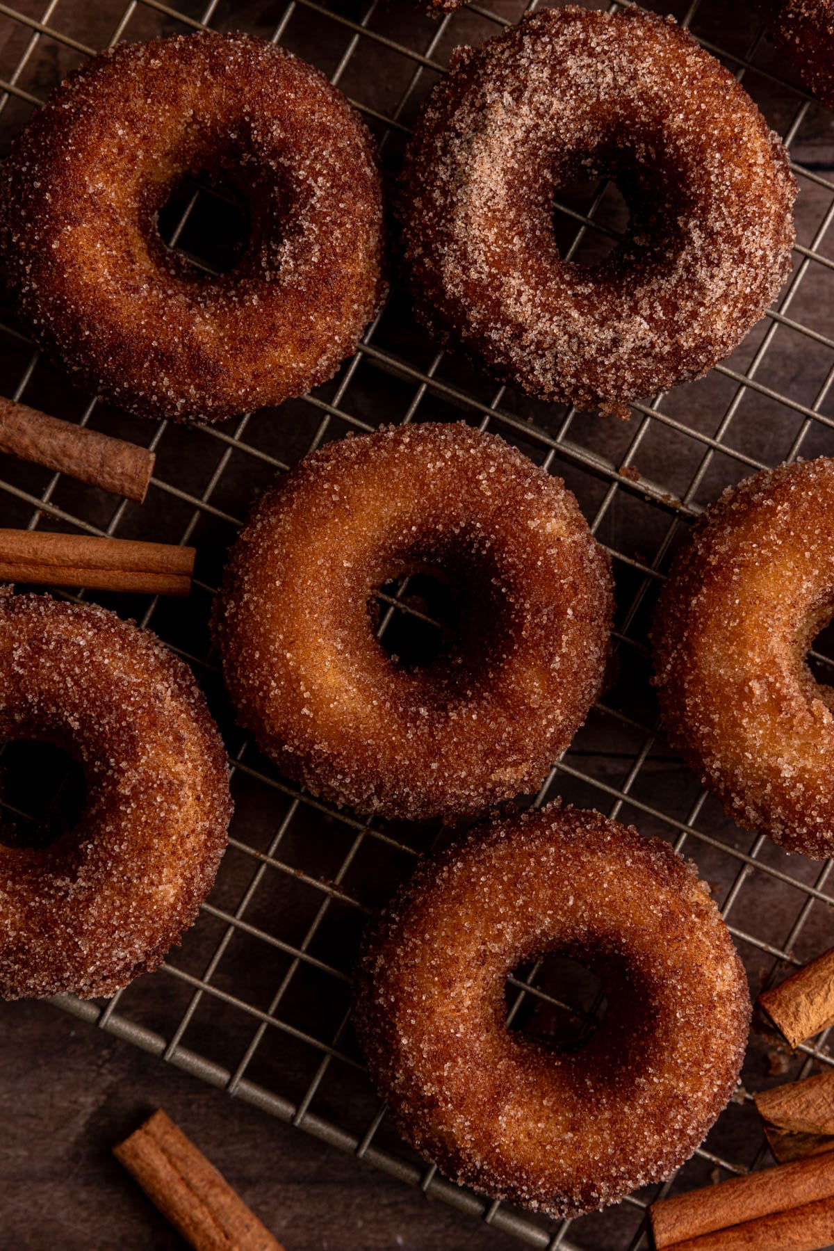 A few vegan cinnamon sugar cake donuts on a wire rack.